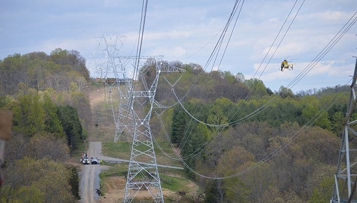 high tension power line being inspected by helicopter