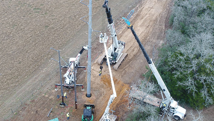 erection of a power pole with trucks and cranes